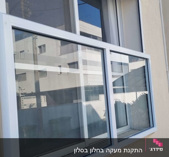 חלון אלומיניום עם מסגרת לבנה על קיר חיצוני
